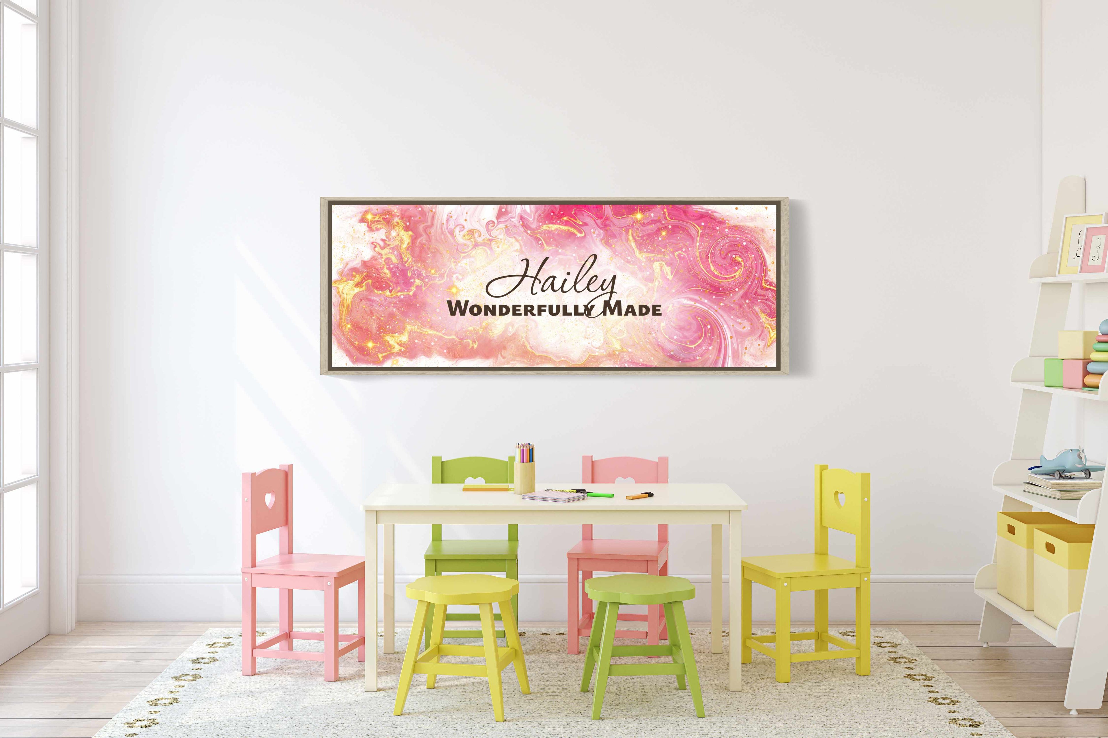 Framed, personalized wall art with ‘Hailey Wonderfully Made' text above a set of table and chairs in a child's playroom
